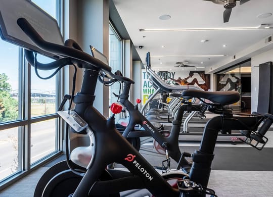 a gym with several bikes in a room next to a window