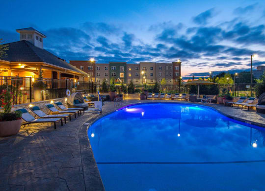 a swimming pool at night with a hotel in the background