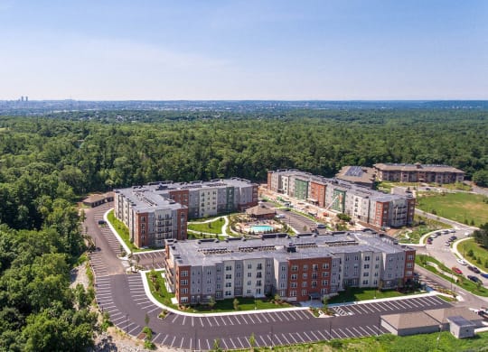 an aerial view of an apartment complex with trees and a parking lot
