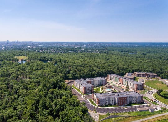 an aerial view of an apartment complex with trees and a city in the distance
