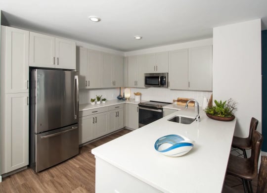 a white kitchen with stainless steel appliances and a white counter top