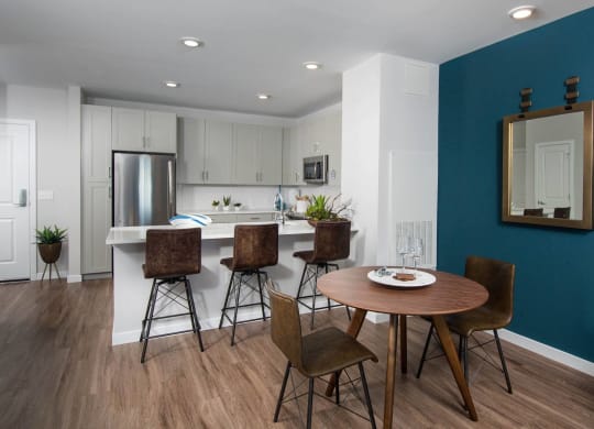Model kitchen and dining room at Alta Clara apartments in Stoneham, MA, featuring wood grain flooring.
