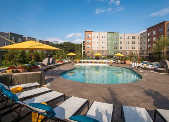 a swimming pool at a hotel with lounge chairs and umbrellas
