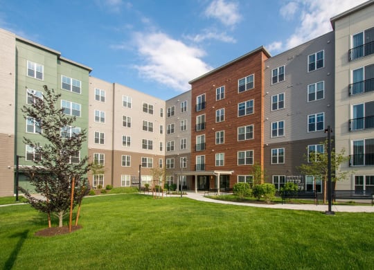 an exterior view of an apartment building with a green lawn