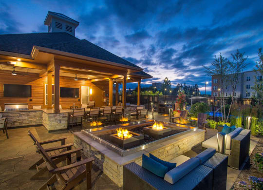 a patio with a seating area and a fire pit at night