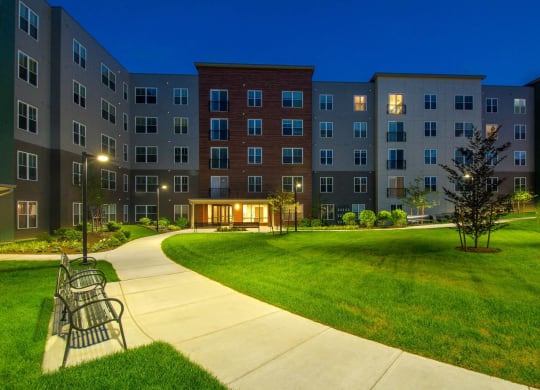 a park with a bench and an apartment building at night