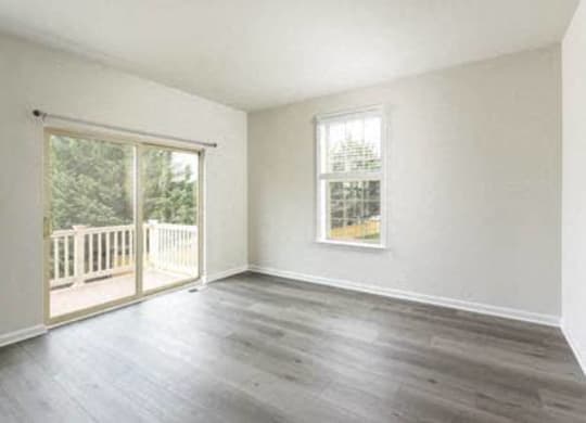 an empty living room with wood floors and a balcony