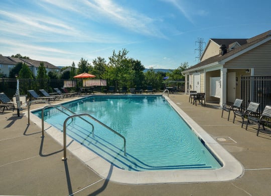 a swimming pool with chairs and a building with a house