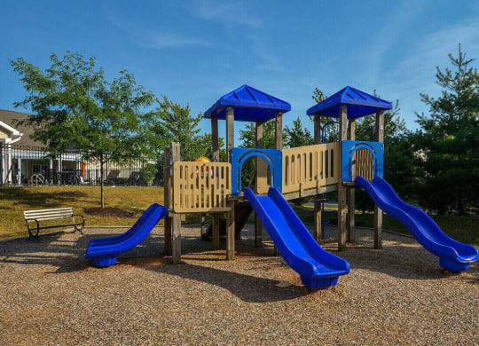 a playground with slides and benches in a park