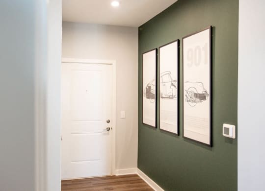 a hallway with a white door and three pictures on the wall