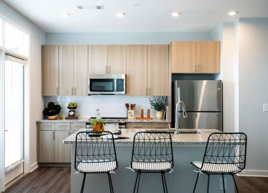 a kitchen with wooden cabinets and a counter with three chairs