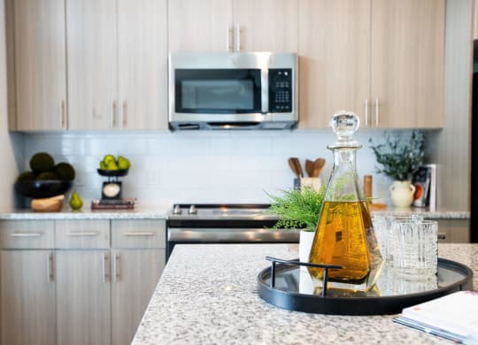 a kitchen counter with a bottle of oil and glasses on it