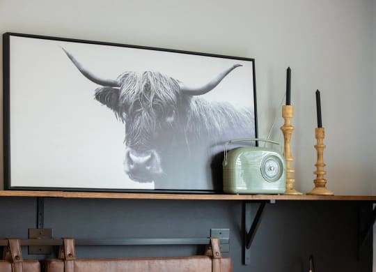 a painting of a cow on a shelf with a radio and a phone