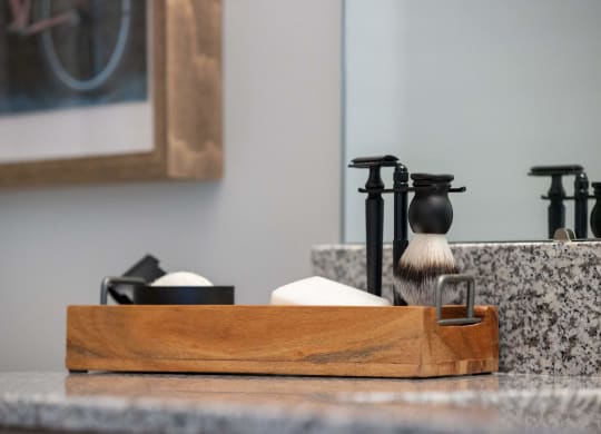 a bathroom sink with a wooden tray with a soap dispenser and a shaving brush