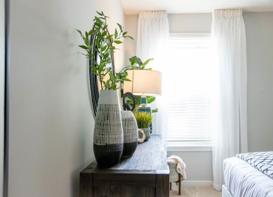 a bedroom with a table with vases and plants on it