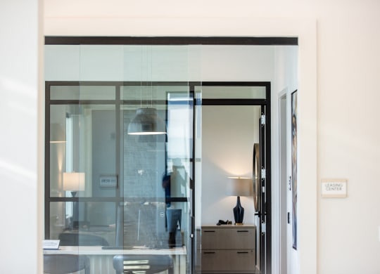 a glass door in a room with a desk and a lamp