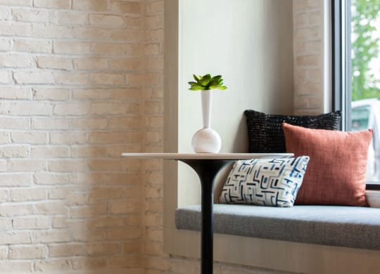 a small table with a vase on it next to a window