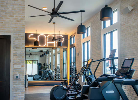 a gym with various workout machines and a ceiling fan