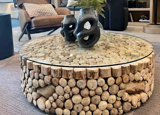 a coffee table made out of logs with two black vases on it