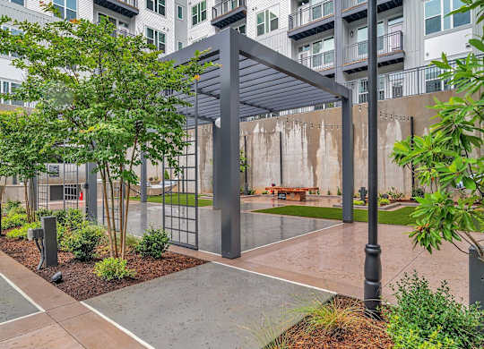 an outdoor courtyard with a bench and trees in front of an apartment building