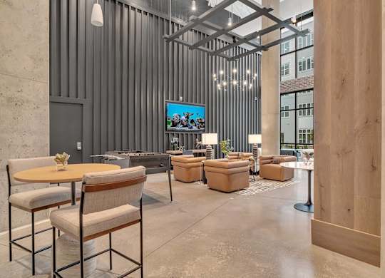 a lobby with chairs and tables and a tv