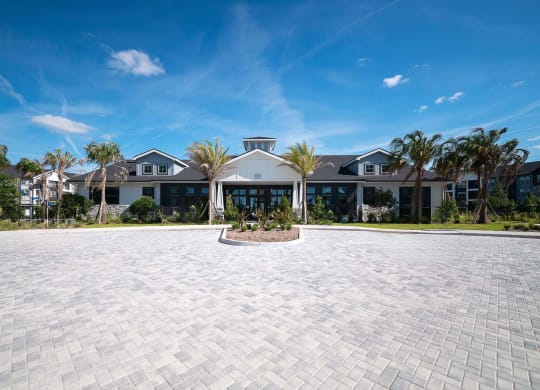 a mansion with a large driveway and a building with palm trees