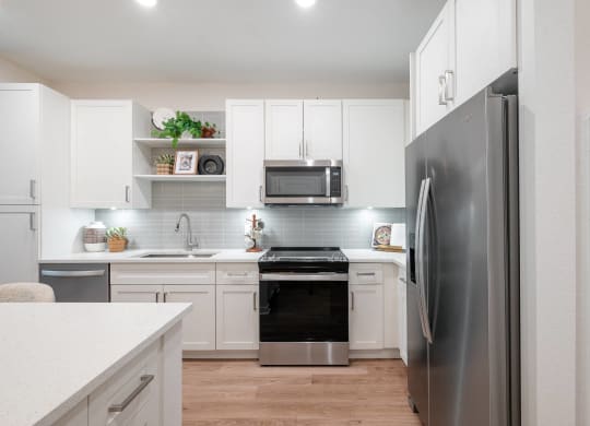 a white kitchen with stainless steel appliances and white cabinets