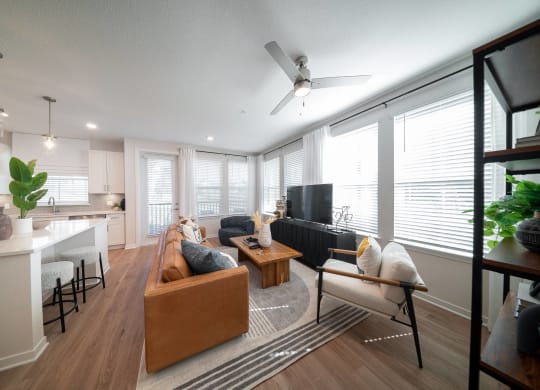 a living room with a couch and a kitchen with a ceiling fan