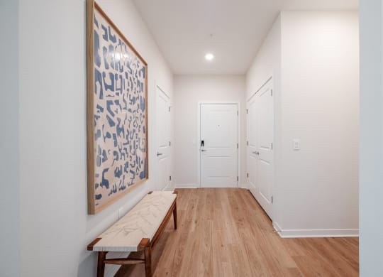 a hallway with a bench and a painting on the wall and white doors