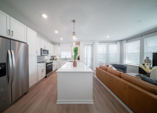 a kitchen and living room with white cabinets and stainless steel appliances
