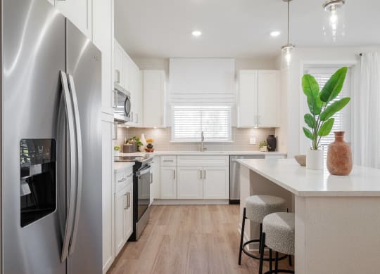 a white kitchen with stainless steel appliances and a white counter top