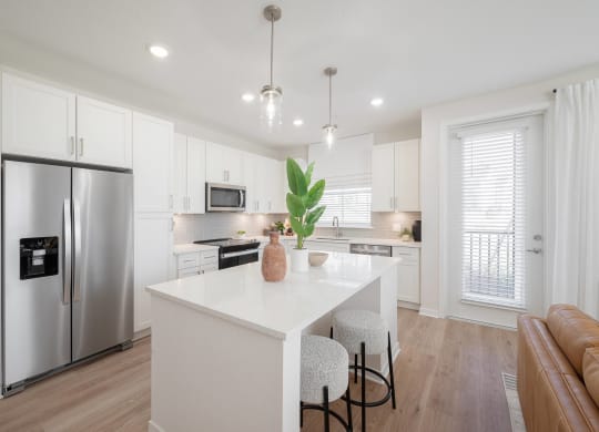 a white kitchen with a white counter top and a stainless steel refrigerator