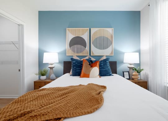 a bedroom with blue walls and a bed with orange and blue pillows