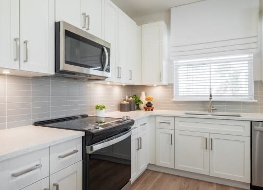 a kitchen with white cabinets and a stove and a microwave