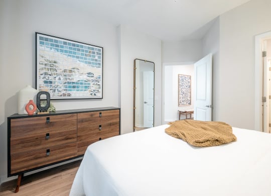 a bedroom with a large bed and a dresser with a mirror