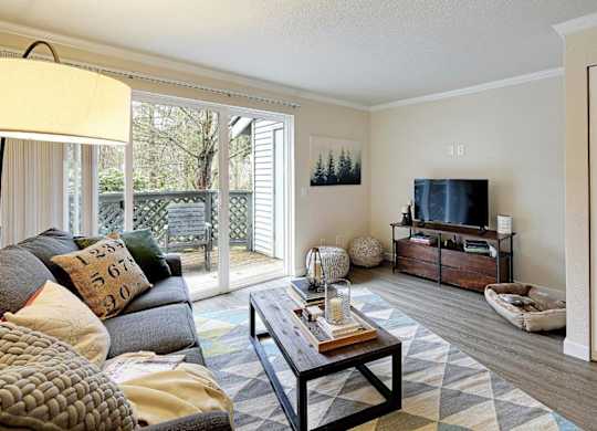 Contemporary living room with patio door and tv console at Hidden River Townhomes Apartments, Washington