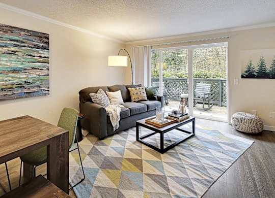 Living room with patio access and geometric area rug at Hidden River Townhomes Apartments, Washington, 98034