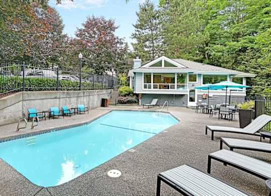 Outdoor swimming pool with lounge seating and clubhouse at Hidden River Townhomes Apartments, Washington