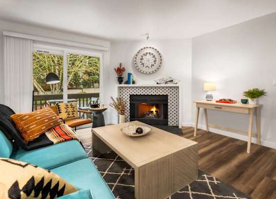 Living room with tiled fireplace and patio access at Scout Apartments, Kirkland, Washington