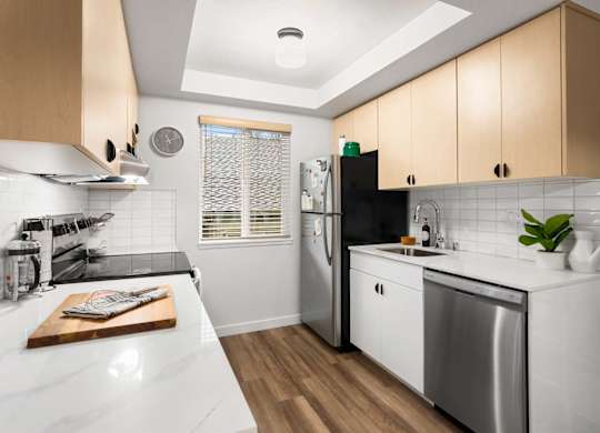 Galley kitchen with wood cabinets and tile backsplash at Scout Apartments, Kirkland, WA