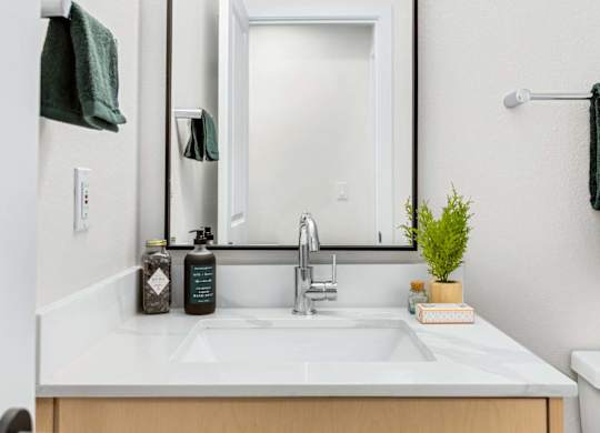 Bathroom vanity with white countertop and framed mirror at Scout Apartments, Kirkland, WA