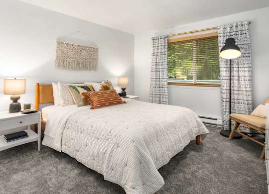 Bedroom with neutral bedding and decorative wall hanging at Scout Apartments, Kirkland, Washington
