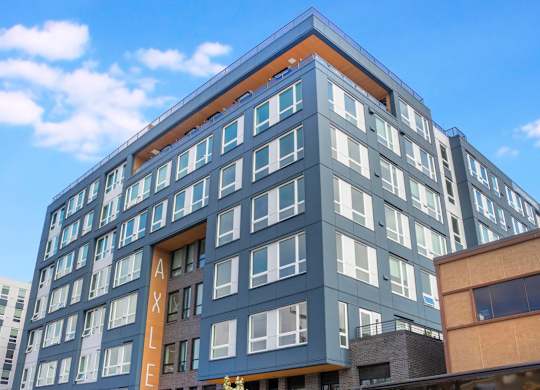 A modern building with a blue and white facade and a large entrance.at Axle, Seattle, WA 98119 
