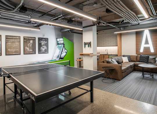A ping pong table is in the middle of a room with a couch and a coffee table.at Axle, Washington 