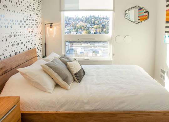 A bedroom with a large bed and a window overlooking a city.at Axle, Washington 