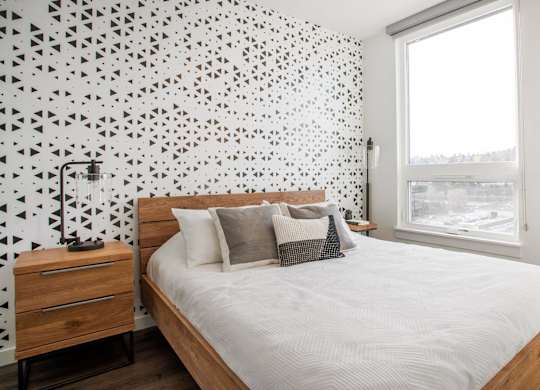 A bedroom with a bed, nightstand, and a wall with a black and white geometric pattern.at Axle, Seattle 
