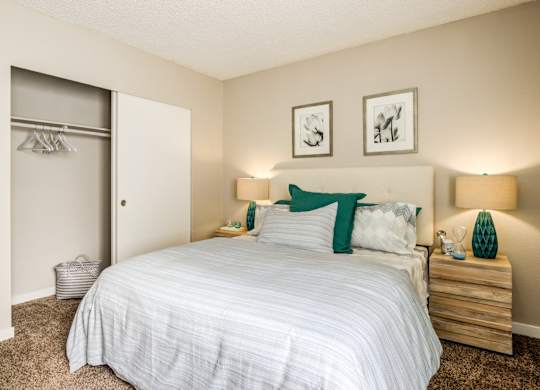 A bedroom with a bed, nightstands, and two pictures on the wall.