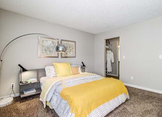 A bedroom with a bed and a yellow blanket.