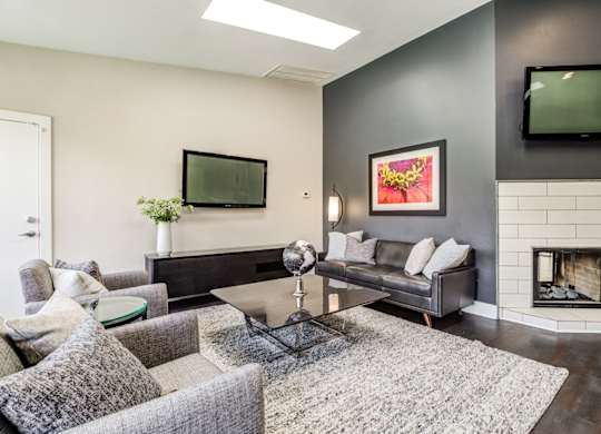 A modern living room with a grey couch, a coffee table, and a fireplace.