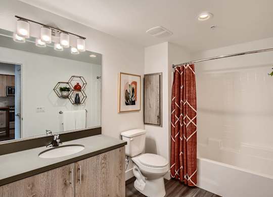A bathroom with a toilet, sink, and a red shower curtain.